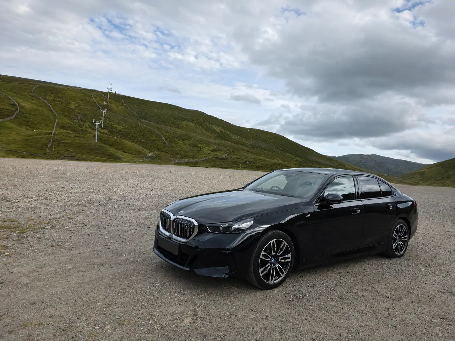 Black BMW i5 executive chauffeur car in the Glenshee mountains